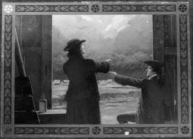 Painting of two men in colonial dress standing at an open doorway, one holding a kite string, gesturing toward a dark stormy sky.