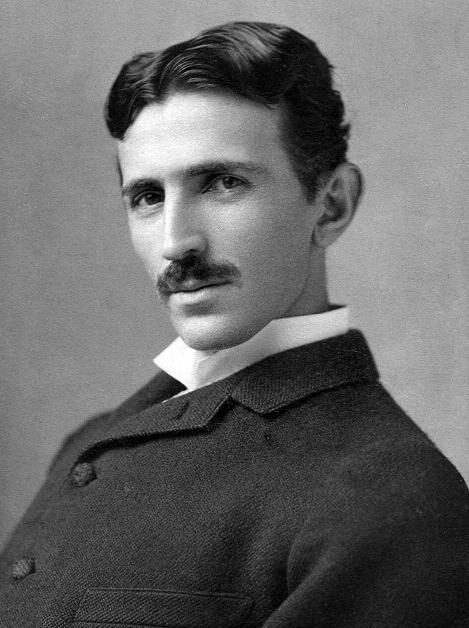 Black-and-white studio portrait of a young man with dark hair and a mustache, wearing a dark coat and white collar.